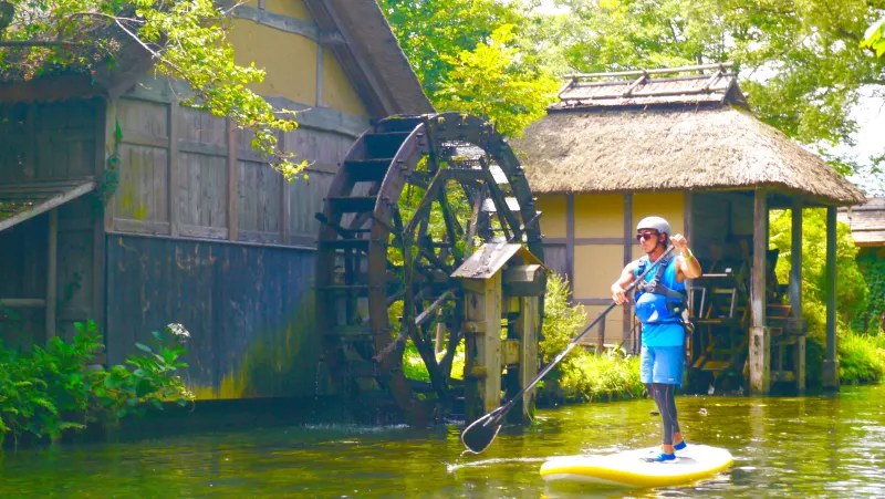 川をSUPで進む工藤晶。水車小屋のある水辺